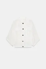 Blusa blanca de cuello solapa, con mangas cortas remangadas por debajo del codo, bolsillos frontales con solapa, bajo elástico y cierre frontal con botones oscuros.