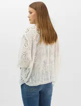 Cardigan abierto estilo kimono, color crudo, con mangas amplias al codo. Presenta una base con textura y motivos florales bordados a tono, con paneles de encaje calado estilo macramé en el frente, puños y ruedo.