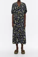 Vestido largo de viscosa con estampado paisley en tonos negro, amarillo y lila. Modelo de corte línea A, escote en V, manga corta y falda con fruncido en el bajo.
