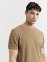 Remera de punto color beige, de manga corta y cuello redondo.