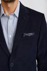 Blazer de pana color marrón oscuro, con cierre frontal de dos botones, solapas clásicas y bolsillos laterales con solapa. Presenta un diseño estructurado y elegante.