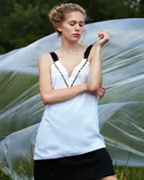 Vestido corto blanco de gasa y seda fina, con escote pronunciado y apliques de perlas de vidrio. Espalda abierta con tirantes cruzados anchos y caída asimétrica.