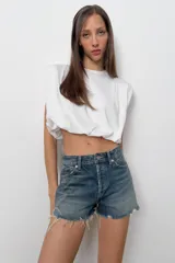 Top de algodón con cuello redondo, diseño sin mangas con hombreras marcadas y detalle de pliegues. Presenta un bajo acabado tipo globo con elástico.