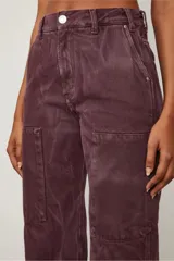 Pantalón de tiro medio color borgoña, con dos parches delanteros que simulan ser bolsillos y costuras visibles.