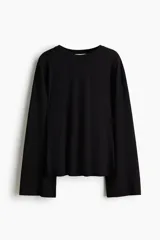 Top de manga larga de algodón y viscosa, color negro, con cuello redondo y mangas acampanadas. Cuenta con hombros levemente caídos y bajo recto con aberturas laterales.