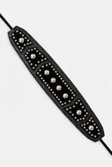 Cinturón tipo faja de cuero negro con tachas plateadas metálicas y tiras colgantes con borlas en los extremos.