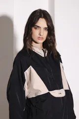 Campera deportiva negra y beige con cierre frontal, cuello alto, puños ajustados y ruedo regulable.