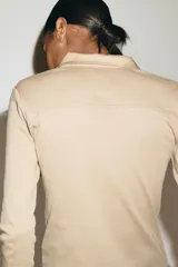 Remera polo de manga larga confeccionada en punto de algodón, con cuello clásico, tapeta frontal con botones y costuras moldeadoras en el frente.