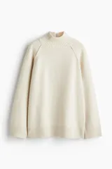 Buzo de punto oversized con cuello tortuga acanalado y abertura en la nuca. Presenta mangas raglán con costuras decorativas y terminaciones acanaladas en puños y bajo.