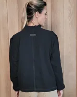 Camisa de manga larga con estampado de rayas verticales en tonos crudo y beige. Presenta cuello alto con volados, cierre frontal con botones dobles y puños con volados.