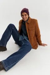 Campera marrón acolchada con cuello camisero, cierre frontal con botones a presión, dos bolsillos de parche en el pecho con solapa y dos bolsillos laterales.