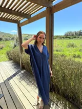 Vestido largo de lino color azul marino, con escote en V y mangas cortas amplias. Presenta un corte relajado y bolsillos laterales.