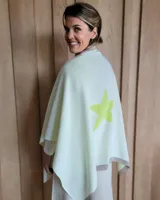 Ruana de tejido de punto en color crema con detalle de estrella grande en color verde lima en la espalda y bordes en tono arena.