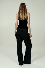 Jean wide leg de tiro alto en denim de algodón negro, con diseño de cinco bolsillos, perneras amplias y cierre frontal con botón y cremallera.