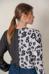 Buzo de manga larga con cuello redondo, combinado en dos tonos: negro liso en la mitad derecha y estampado animal print blanco y negro en la mitad izquierda.