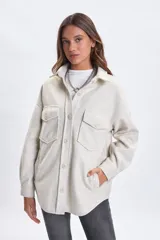 Sobrecamisa de paño en color beige, con cuello camisero, cierre frontal de botones y dos bolsillos delanteros con solapa. Presenta un corte holgado y mangas largas.