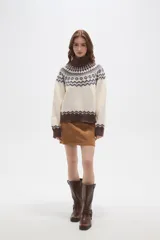 Sweater de punto con diseño jacquard en cuello, puños y ruedo. Presenta cuello alto, mangas largas y corte holgado.