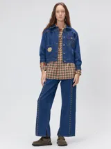Campera denim crop de mezclilla oscura, con apliques metálicos en el pecho, bolsillos delanteros cruzados con detalles bordados y de parches.
