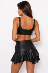 Top corto engomado de diseño audaz, con tirantes anchos con hebillas ajustables estilo arnés y bandas horizontales con hebillas frontales.