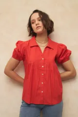 Camisa roja con cuello clásico, mangas cortas abullonadas y cierre frontal con botones.