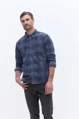 Camisa de manga larga confeccionada en viyela de algodón con estampado de cuadros en tonos azules. Presenta cuello clásico, cierre frontal con botones y un bolsillo aplicado en el pecho.