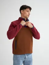 Buzo de polar color borgoña y marrón, con cuello alto con botones a presión y bolsillos laterales.