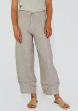Pantalón de lino color beige con rayas verticales finas, corte amplio y tobillos ajustados.