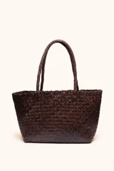 Bolso tipo tote de cuero vacuno, completamente trenzado a mano. El color es marrón oscuro, casi chocolate. Posee dos asas de hombro trenzadas.