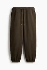 Pantalón deportivo de felpa en mezcla de algodón con interior cepillado. Presenta cintura elástica con cordón de ajuste, bolsillos laterales y puños acanalados en los tobillos.