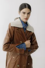 Trench de cuero color camel, doble botonadura, cuello con solapas y forro de piel sintética.