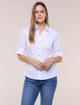 Camisa blanca de poplín de algodón, semi entallada, con cuello camisero, escote en V y botones metálicos a presión. Cuenta con mangas 3/4 arremangables con presilla y argolla metálica, dos bolsillos en el pecho y paneles laterales elásticos.