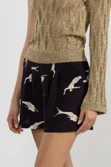 Shorts negros con estampado de sirenas blancas, cintura elastizada, pliegues al frente y bolsillos laterales.