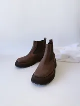 Bota Chelsea de cuero color marrón chocolate con elástico lateral negro y suela track color negro.