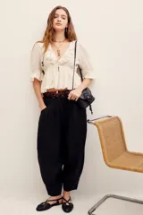 Pantalón babucha negro de lino, de corte holgado estilo barrel con pinzas en la cintura y bolsillos laterales.