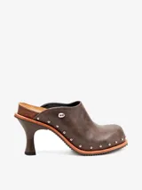 Zueco marrón de cuero con tacón de aguja, punta cerrada y apliques metálicos plateados.