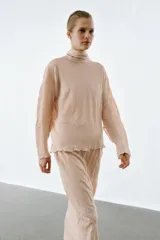 Falda midi de punto color rosado con efecto arrugado, cintura elástica y detalle de volados en la parte superior.