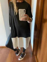 Remerón negro con corte evasé y detalle de bloque blanco en el ruedo.