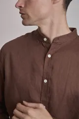Camisa de lino color marrón, con cuello mao, manga larga y botones blancos.