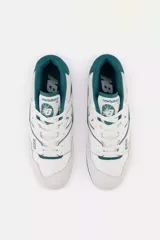 Championes urbanos New Balance modelo 550, con diseño retro inspirado en el básquet, combinando cuero blanco con detalles en gamuza gris y acentos en color verde oscuro.