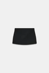 Falda pantalón de tiro bajo en color negro. Presenta falsos bolsillos de vivo en la parte delantera y cierre lateral con cremallera oculta en la costura.
