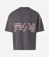 Remera gris oscuro de corte oversized con cuello redondo y manga corta. Cuenta con estampa frontal en color rosado con texto "LEAD THE WAY", tres estrellas y grafismo de números.