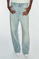 Jeans baggy de tiro medio, pierna ancha y diseño de cinco bolsillos, confeccionados en denim celeste con aplicaciones de brillos en los laterales.