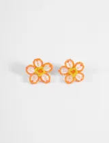 Aros tipo caravanas con diseño de flor, elaborados artesanalmente con mostacillas en tonos naranja y amarillo, y centro con cuentas de cristal transparente.