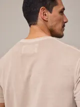 Remera beige de piqué con cuello redondo y logo bordado en blanco.