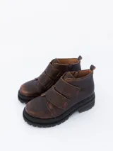 Botines de cuero color marrón chocolate, con ajuste mediante tiras con velcro y suela de goma negra.