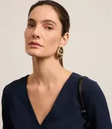 Blusa Cortelle de corte holgado confeccionada en crepé, con escote en V delantero y trasero, y mangas cortas. Presenta una tira decorativa entre los hombros en la espalda.
