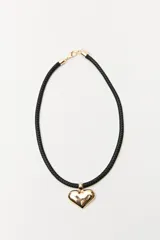 Collar con cadena de cordón trenzado negro y dije dorado en forma de corazón.