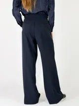 Pantalon de vestir de corte sastrero y tiro alto, con pinzas frontales, cierre de doble botón y pernera ancha.