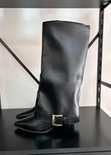 Botas altas de ecocuero color negro, con diseño de caña ancha, punta fina y taco kitten. Incluyen una tira con hebilla metálica dorada decorativa en la base.