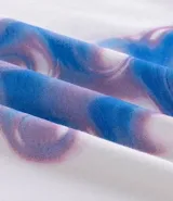 Remera de algodón color blanco tiza, manga corta y cuello redondo. Presenta un estampado grande en la espalda con la palabra "Creative" en tipografía cursiva iridiscente, un oso de goma con efecto holográfico en tonos azules y rosados, y el texto "MATTERS MORE THAN P¡FORMACE" debajo.